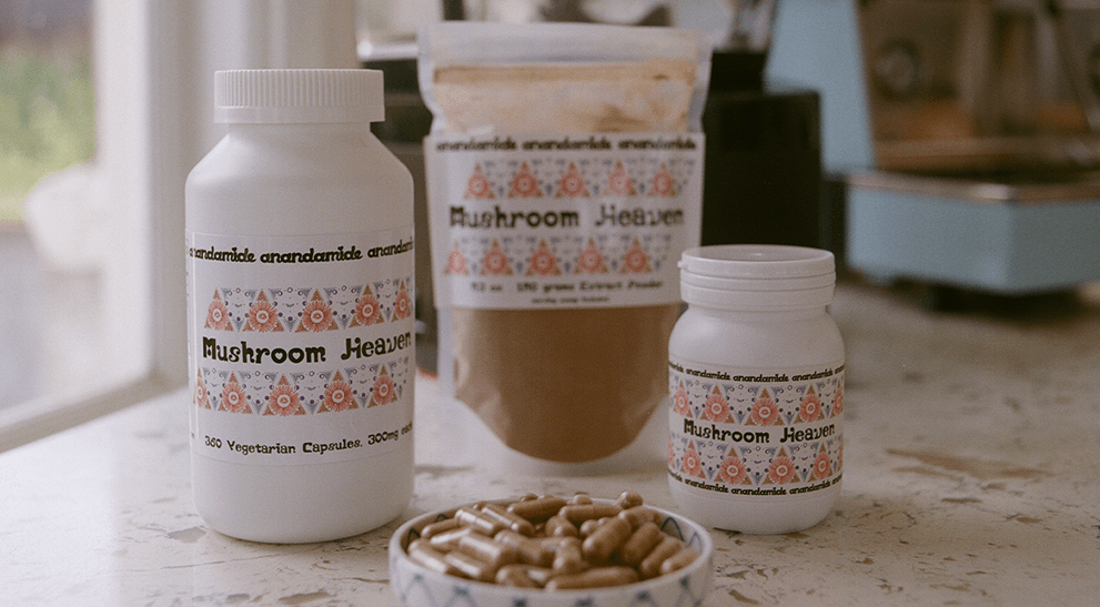 Bottles and a bowl of 'Mushroom Heaven' products on a surface with a blurred background.